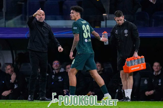 Nico O'Reilly, pemain dari Manchester City, tampak berdiri di sebelah pelatih Pep Guardiola saat pertandingan Liga Champions melawan Real Madrid hari Rabu (10/12/2025).